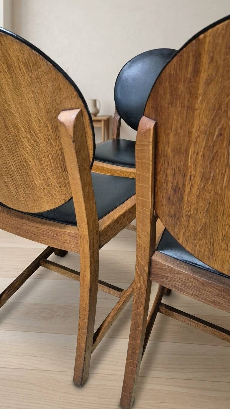 Set of four vintage wooden dining chairs with black leather upholstery