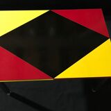Table basse pieds métal, revêtement formica, design géométique noir rouge et jaune