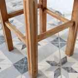 Vintage low stool in rustic style made of wood with a straw seat.
