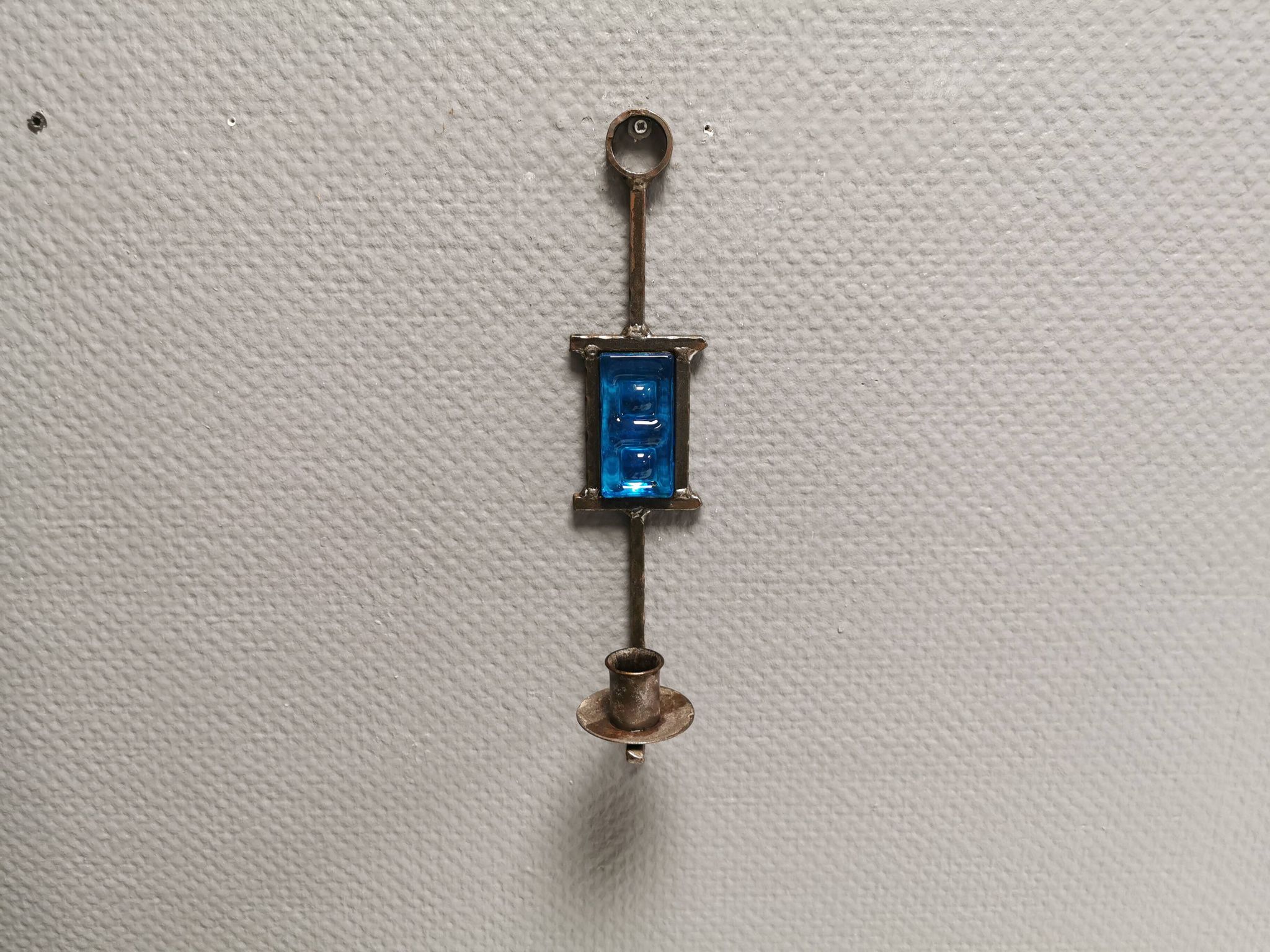 Wall-mounted candle holder in cast iron and hard pressed blue glass.