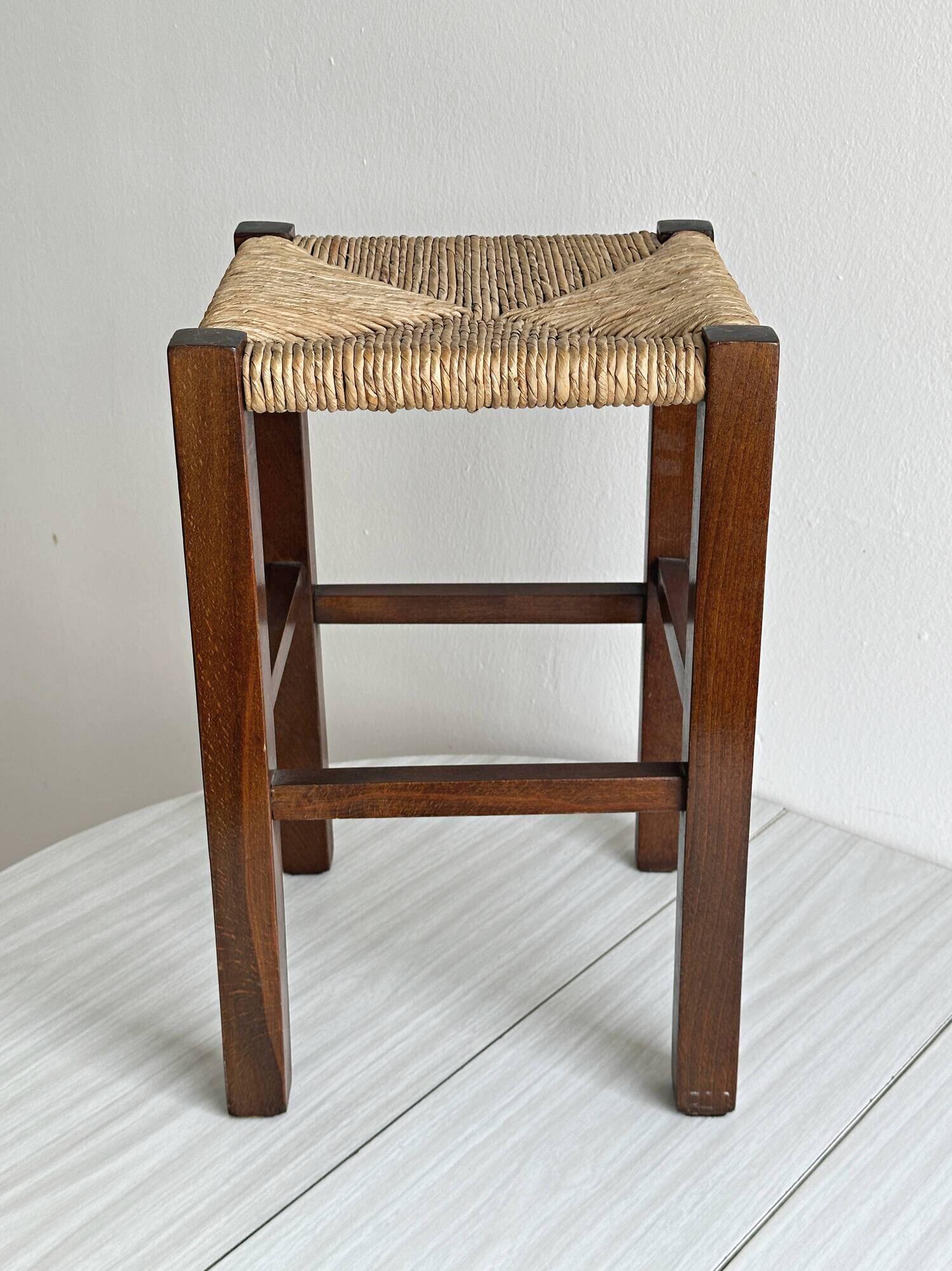 Vintage stool in dark wood with a woven straw seat.