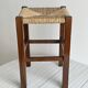 Vintage stool in dark wood with a woven straw seat.