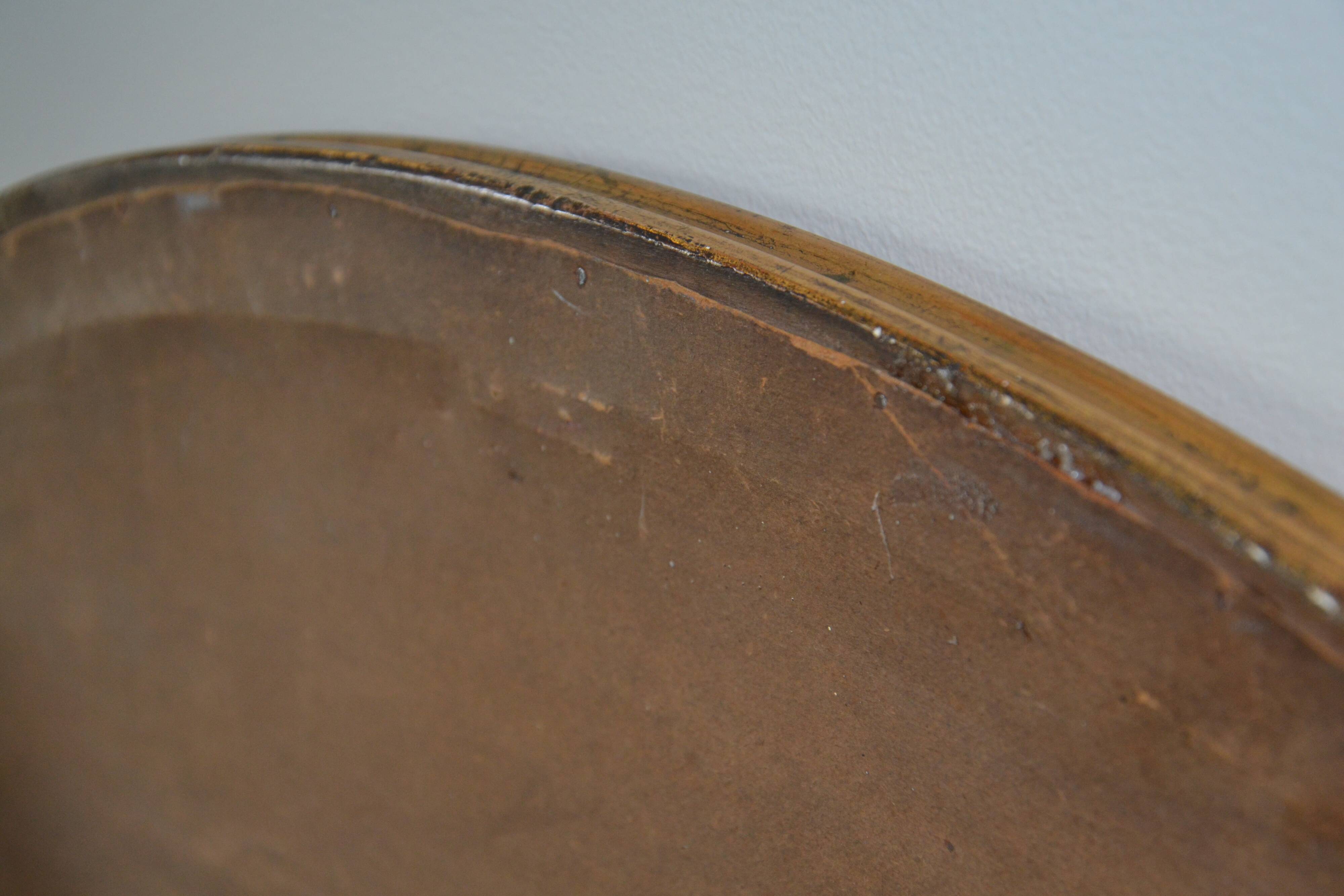 Old oval beveled wooden mirror, partly gilded and carved