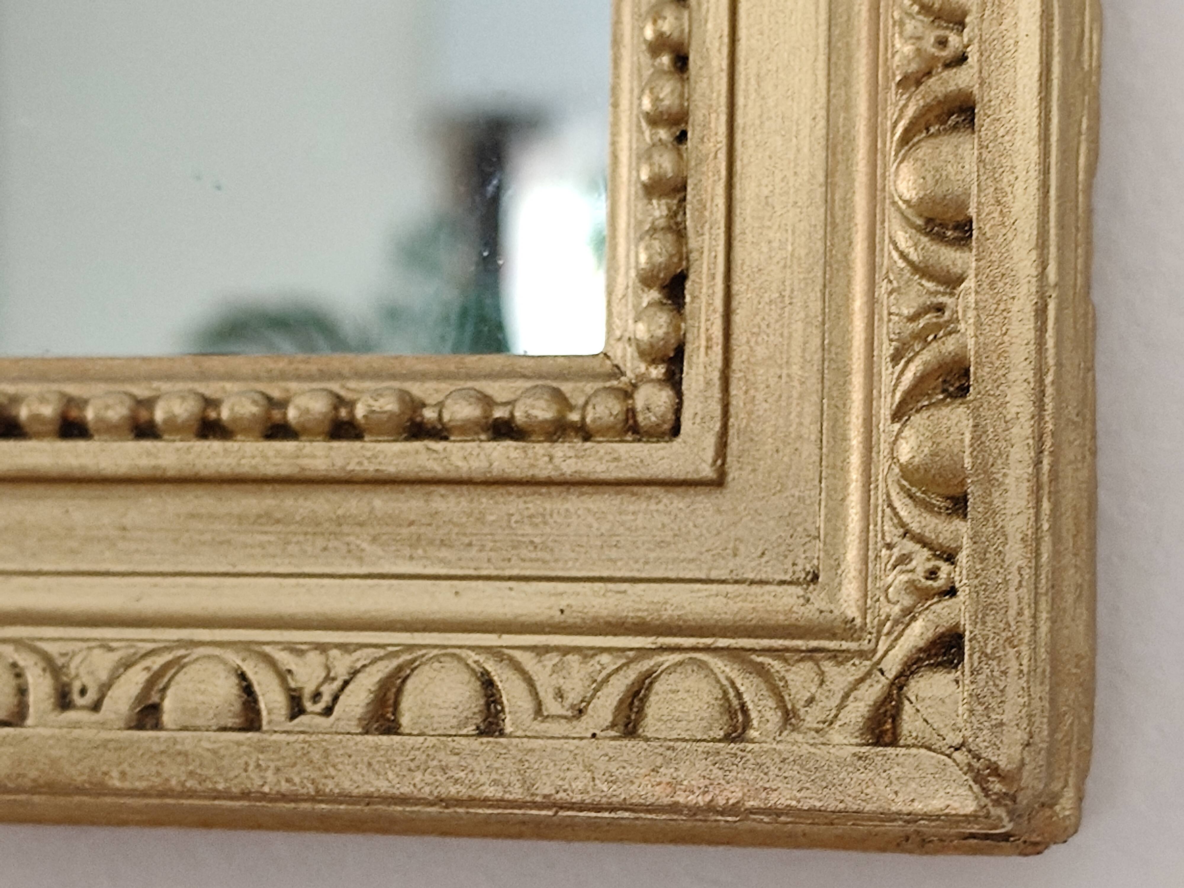 Antique mirror with a gilded frame and beaded border.