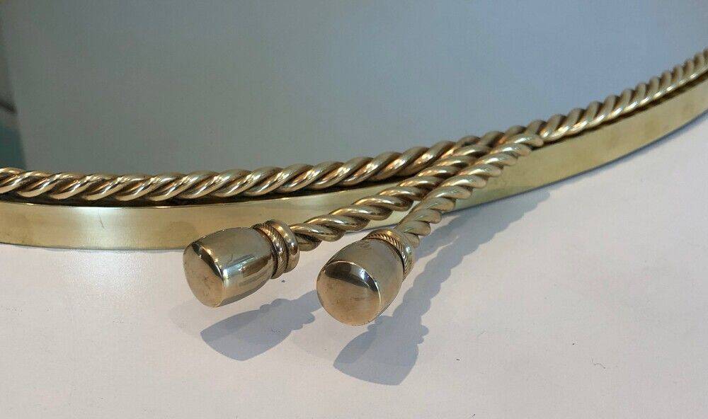 Oval brass mirror surrounded by a cord.