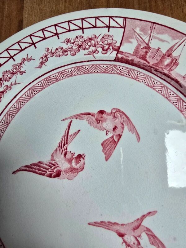 A pair of old flat plates with red and blue bird patterns.