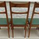 6 modern chairs with banded backs and green faux leather seats.