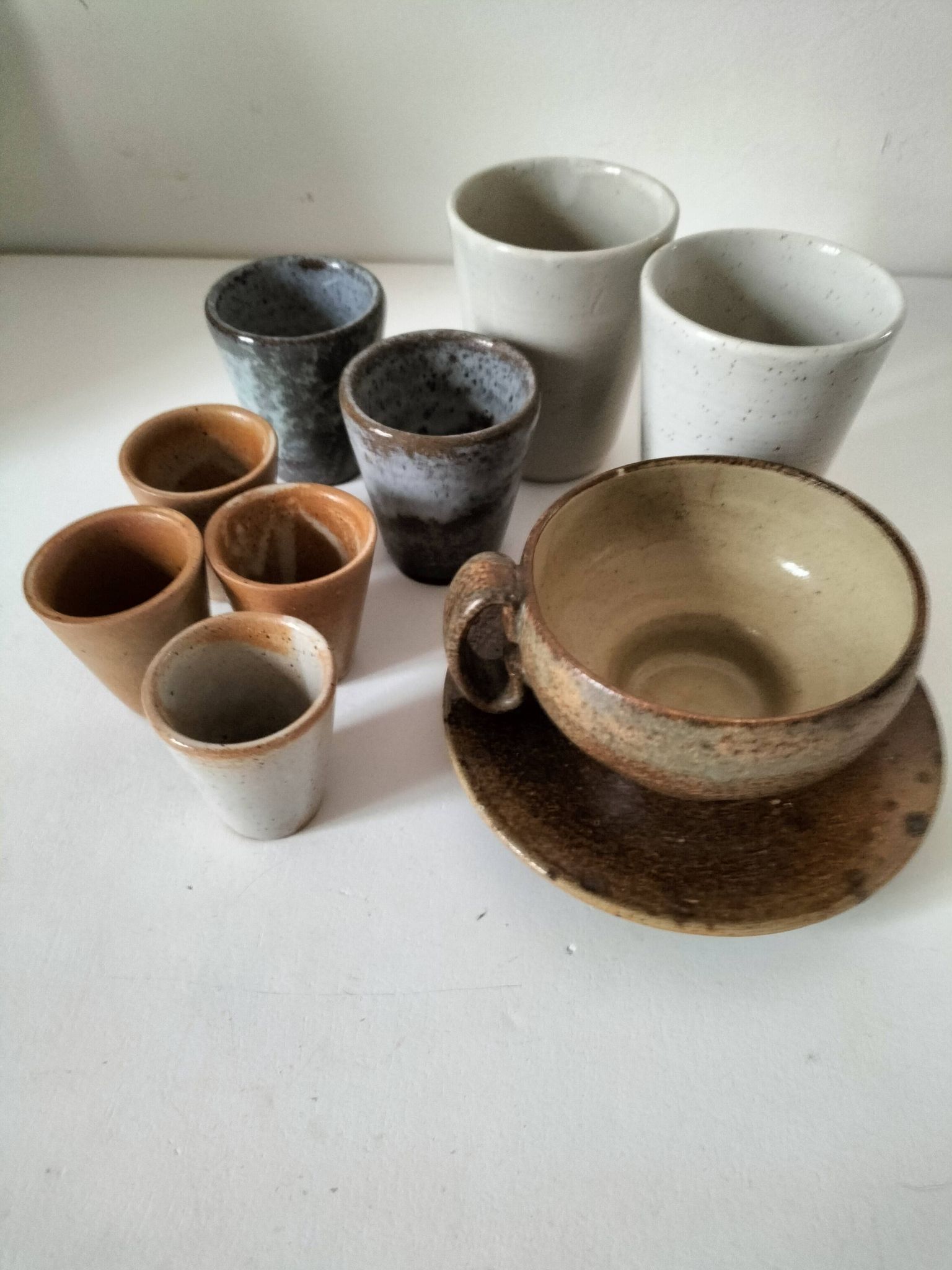 Set of 8 stoneware cups and a mug, shades of beige.