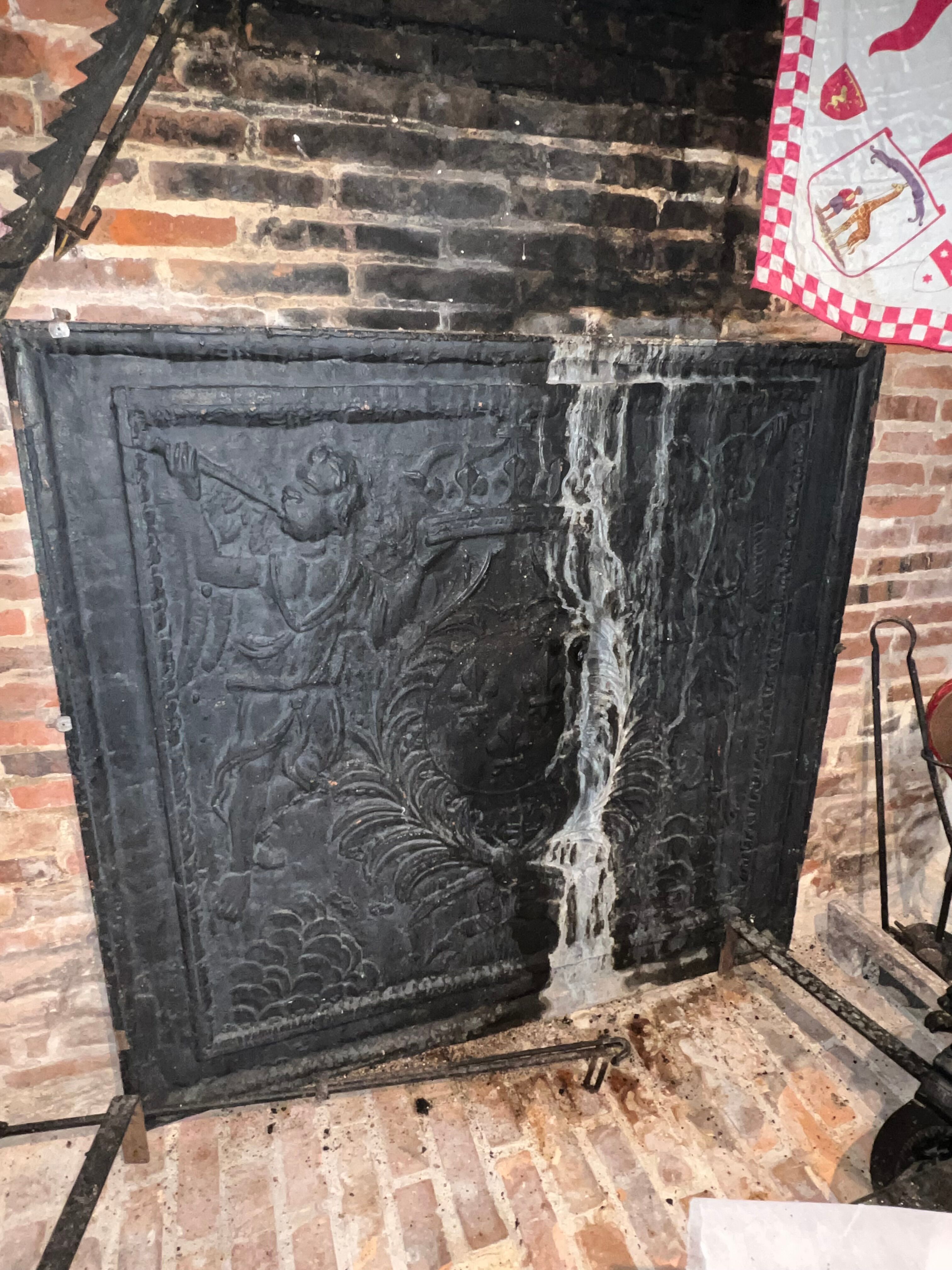 huge old fireplace plate has decoration of angels, crown and fleurs-de-lis