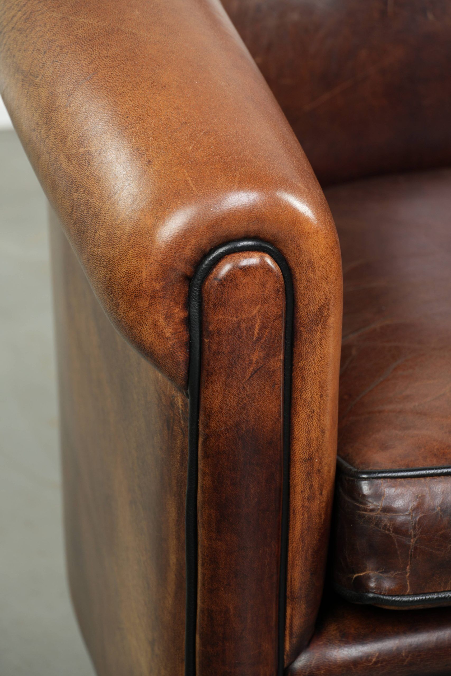 Sheepskin club armchair with deep warm colours and black piping