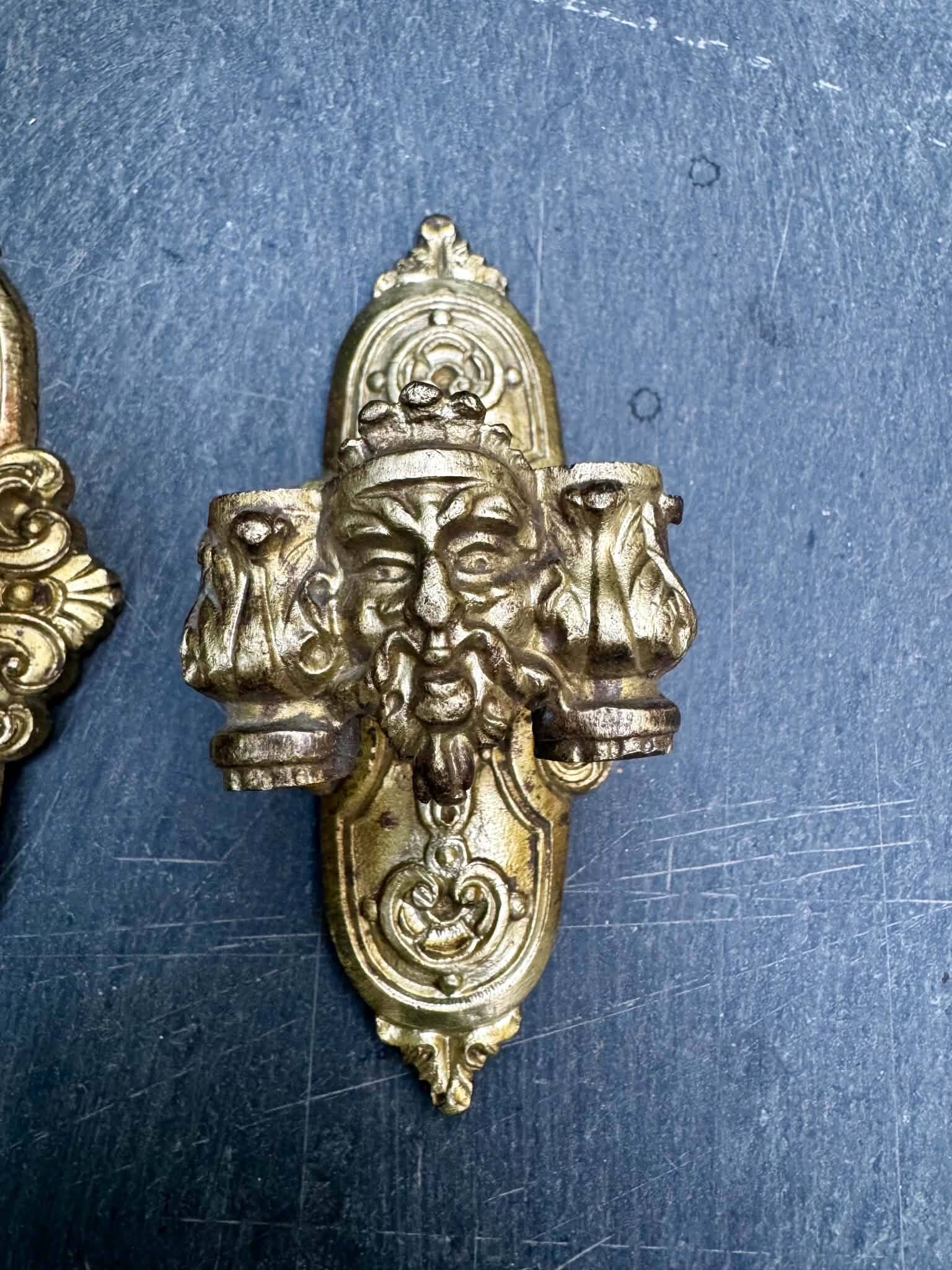 Pair of bronze wall sconces with mask, signed L. Pinet, Art Nouveau period.