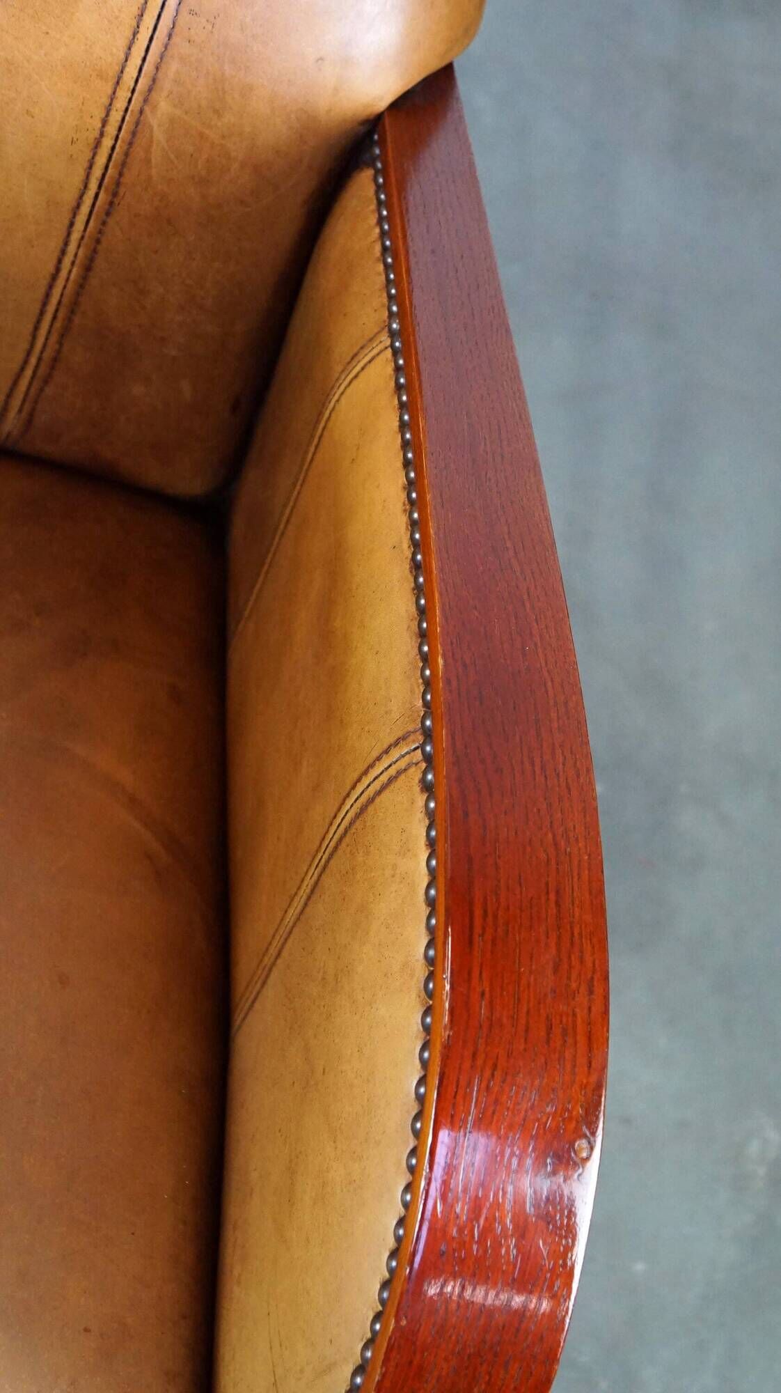 Luxurious cowhide Art Deco design armchair with wooden armrests and cognac-colored leather