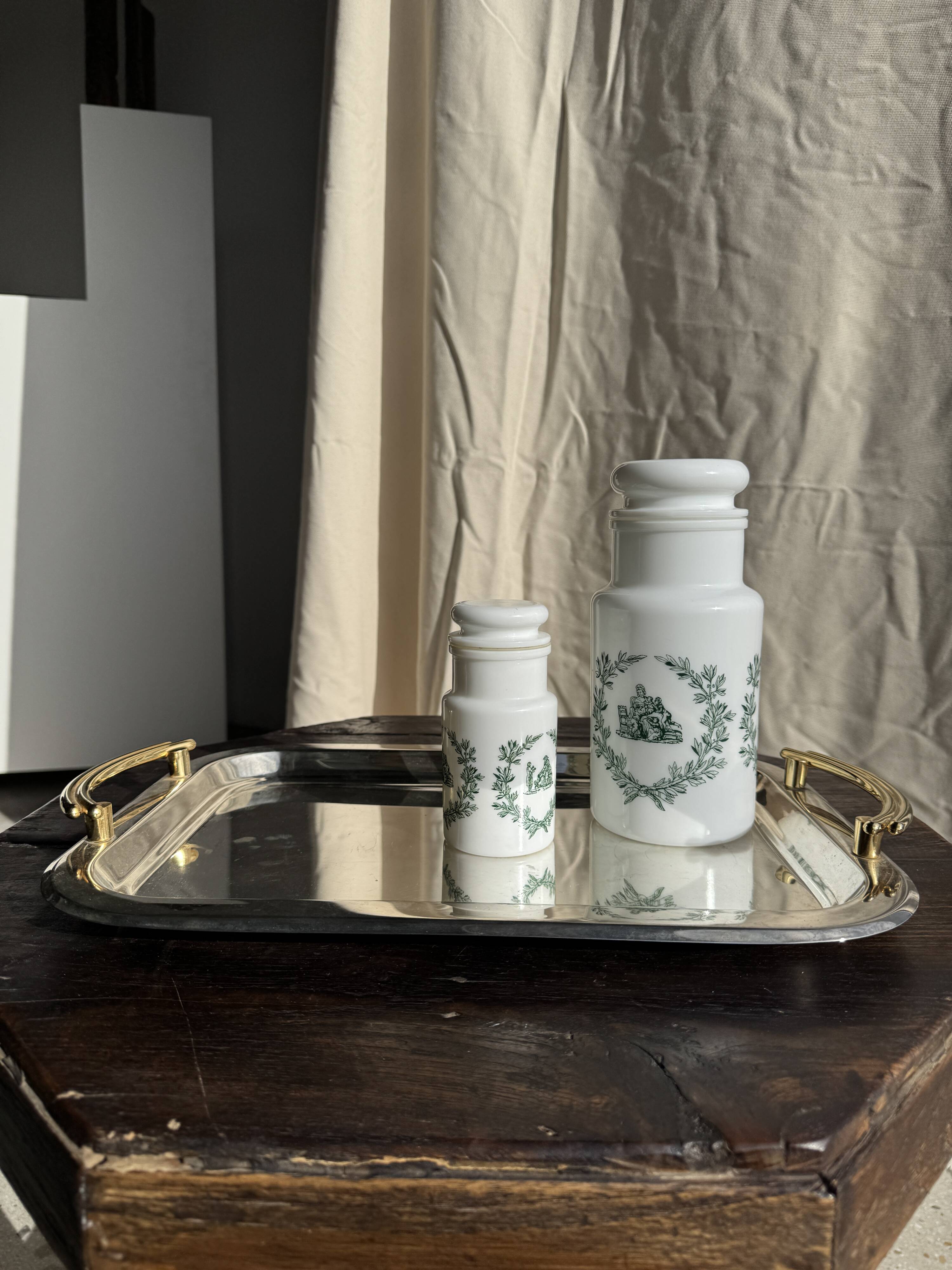 A pair of white glass bottles with Italian green patterns.