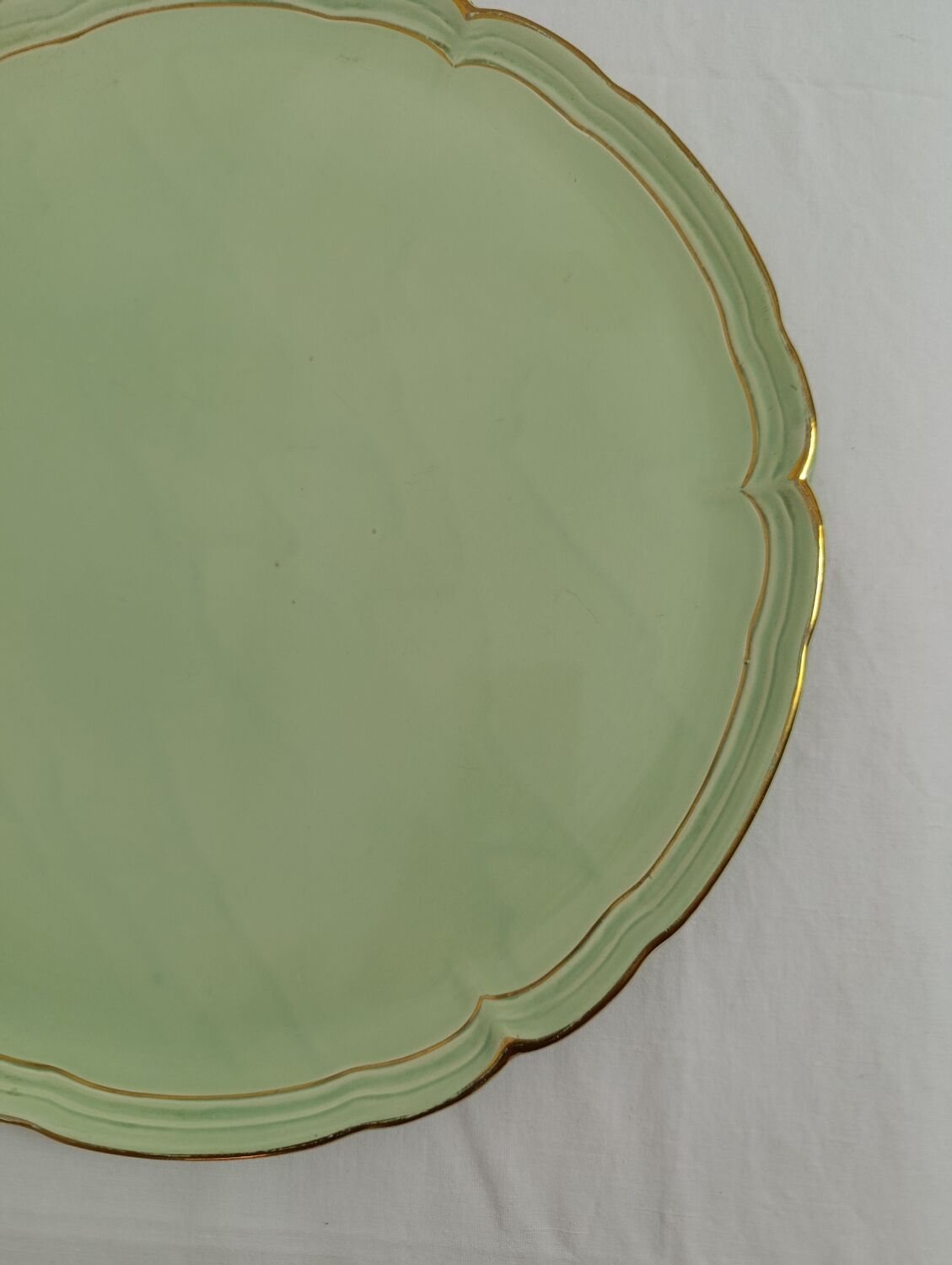 Large pastel green plate with a golden rim.