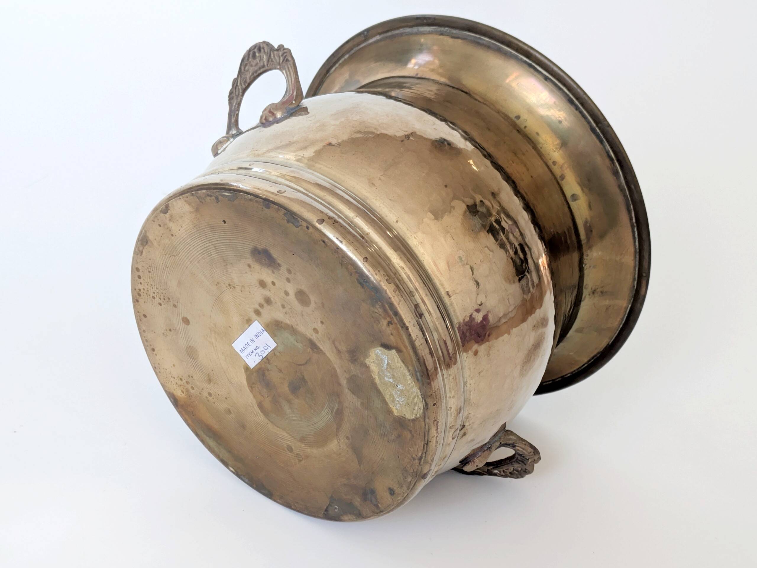 Vintage round cache-pot in hammered brass with decorative handles and patina.