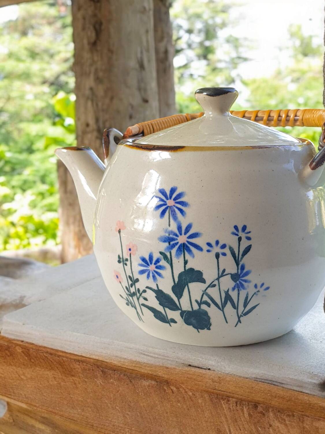 Théière en grès fleurie et anse en rotin.