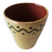 Mustard-colored ceramic cup or glass with green decor
