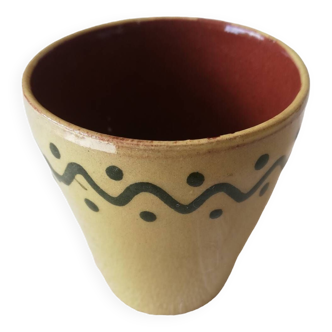 Mustard-colored ceramic cup or glass with green decor