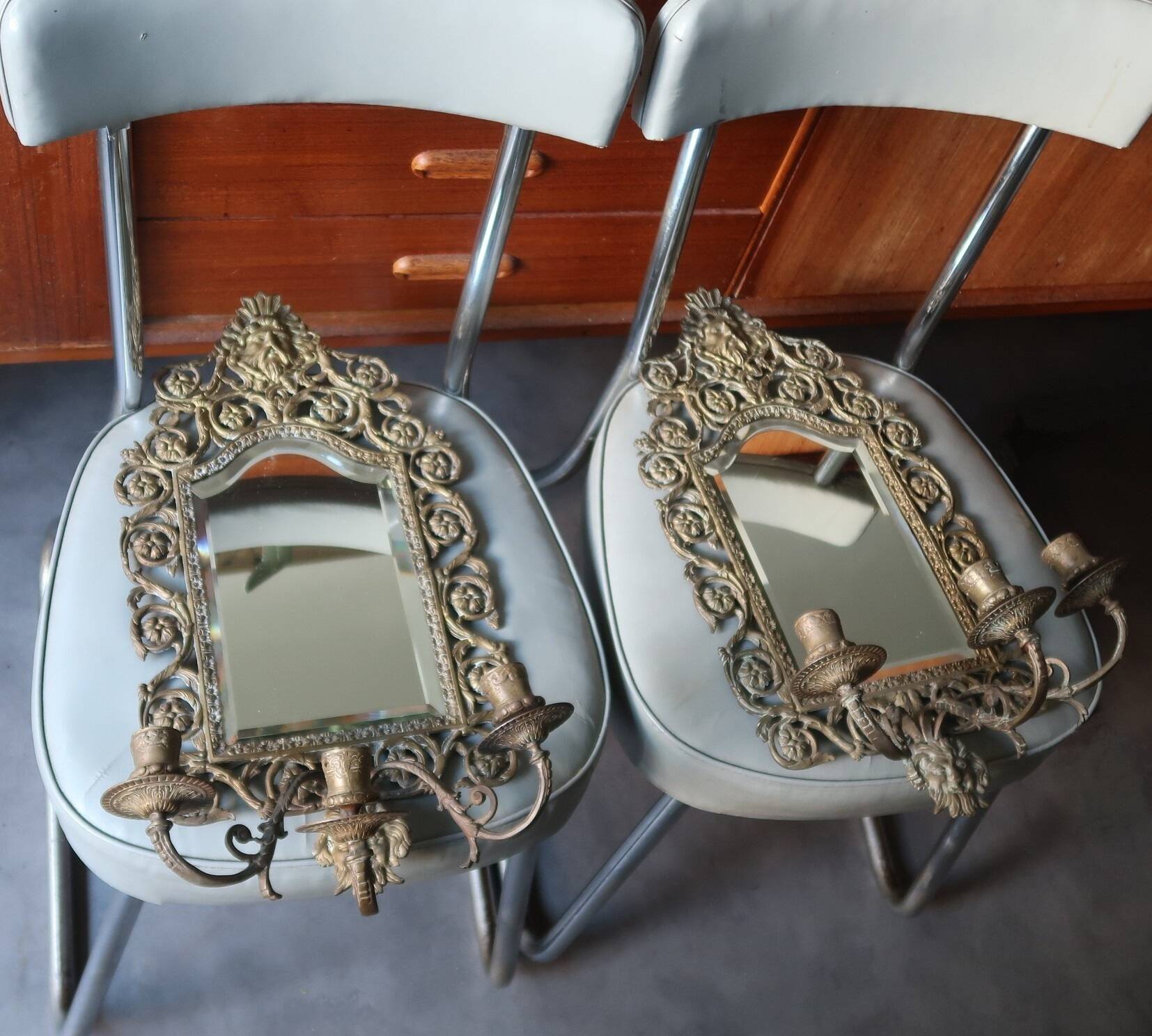 Pair of mirror wall sconces with brass candle holders.