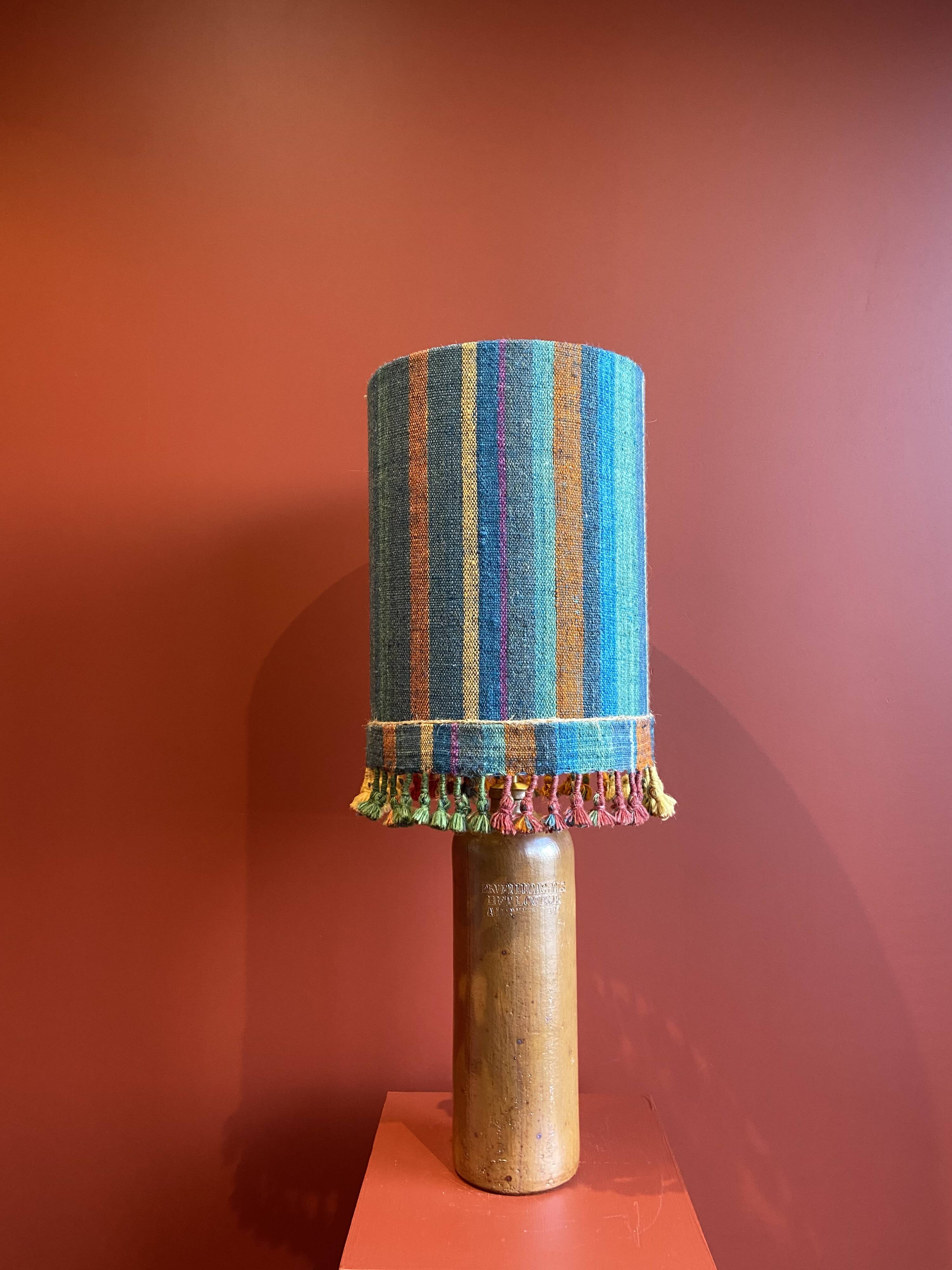 "Stoneware Bottle Lamp" with a multicoloured blue lampshade handwoven in India.