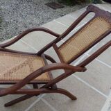 Antique folding chair with caned seat and backrest made of wood.