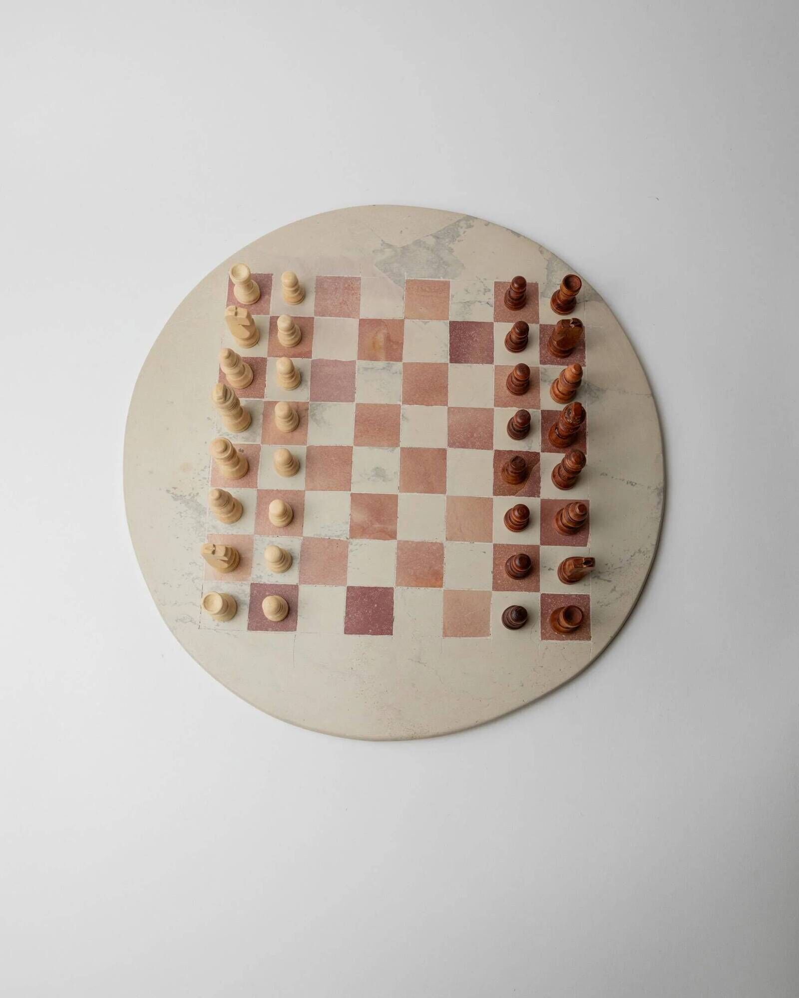 Vintage 1980s round chess set in marble, with a beige and pink marble board and wooden pieces.