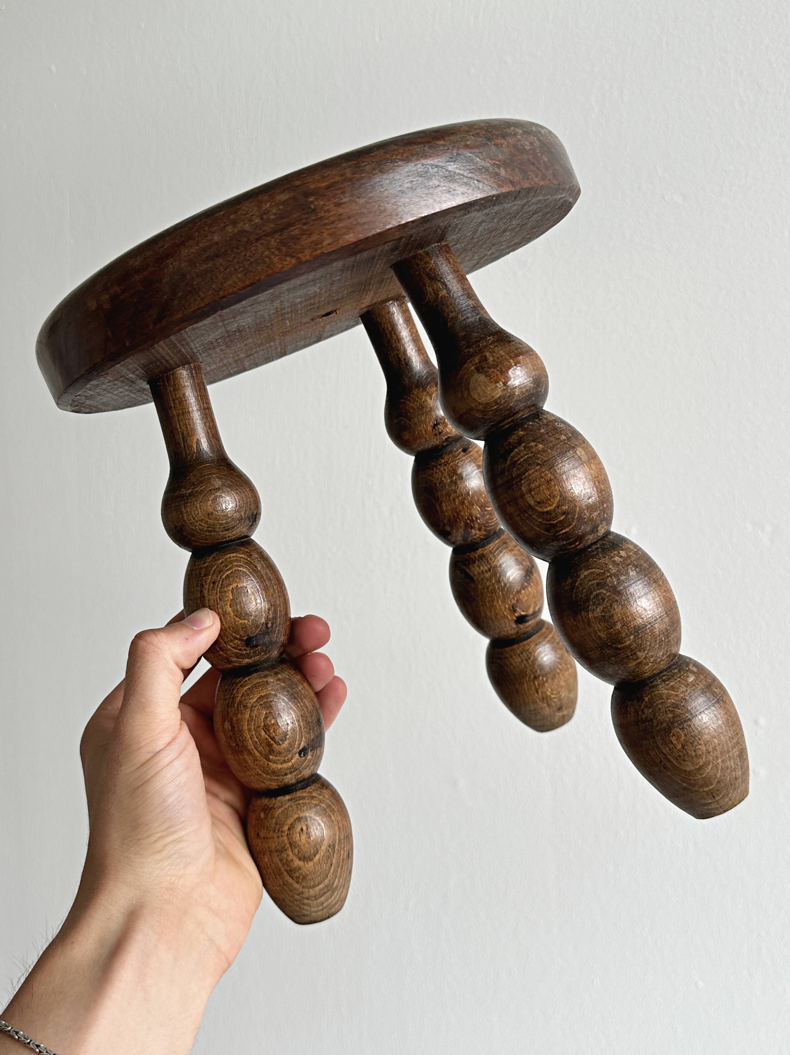 Small three-legged stool made of turned wood.