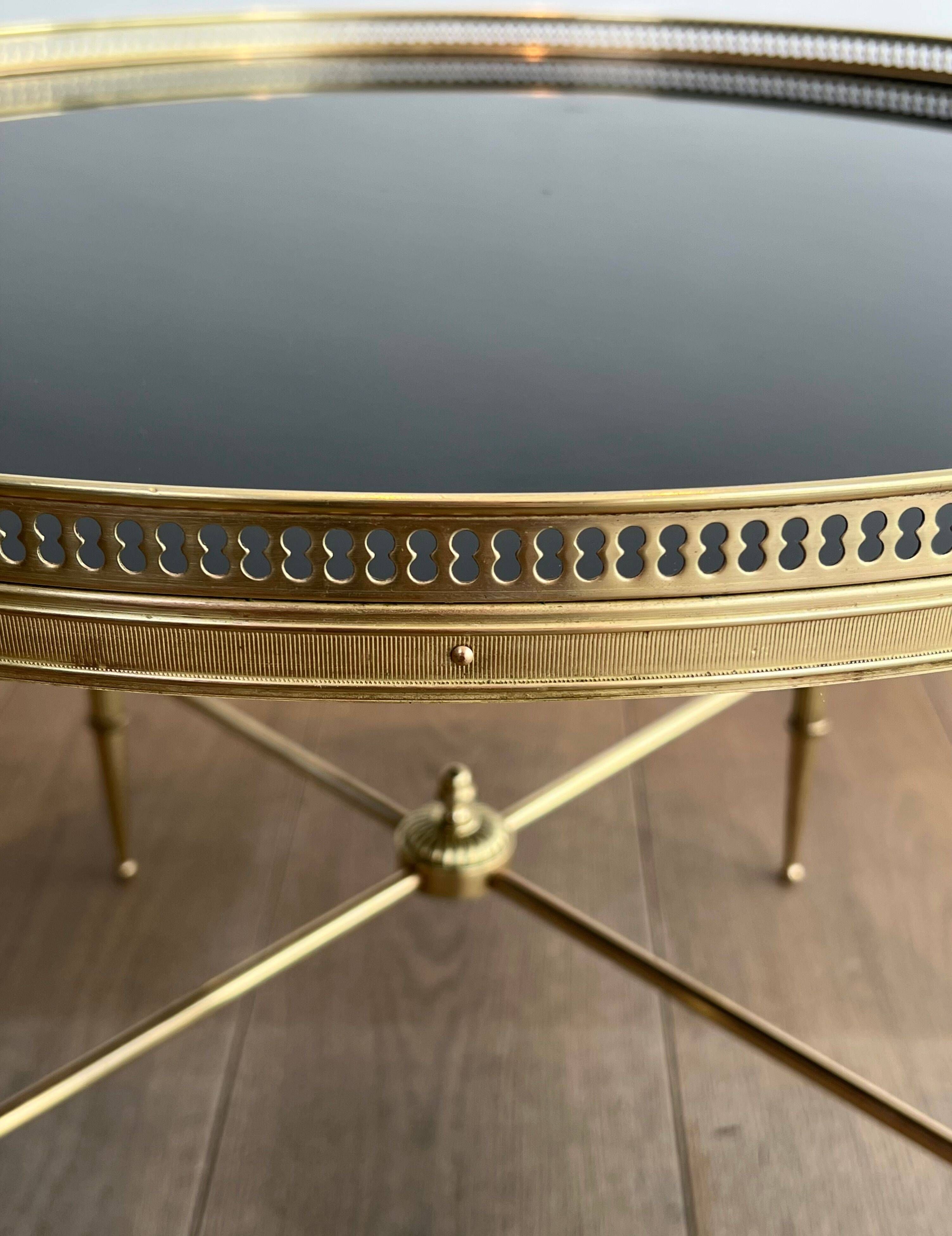 Round coffee table in brass with a black lacquered glass top from Maison Jansen.