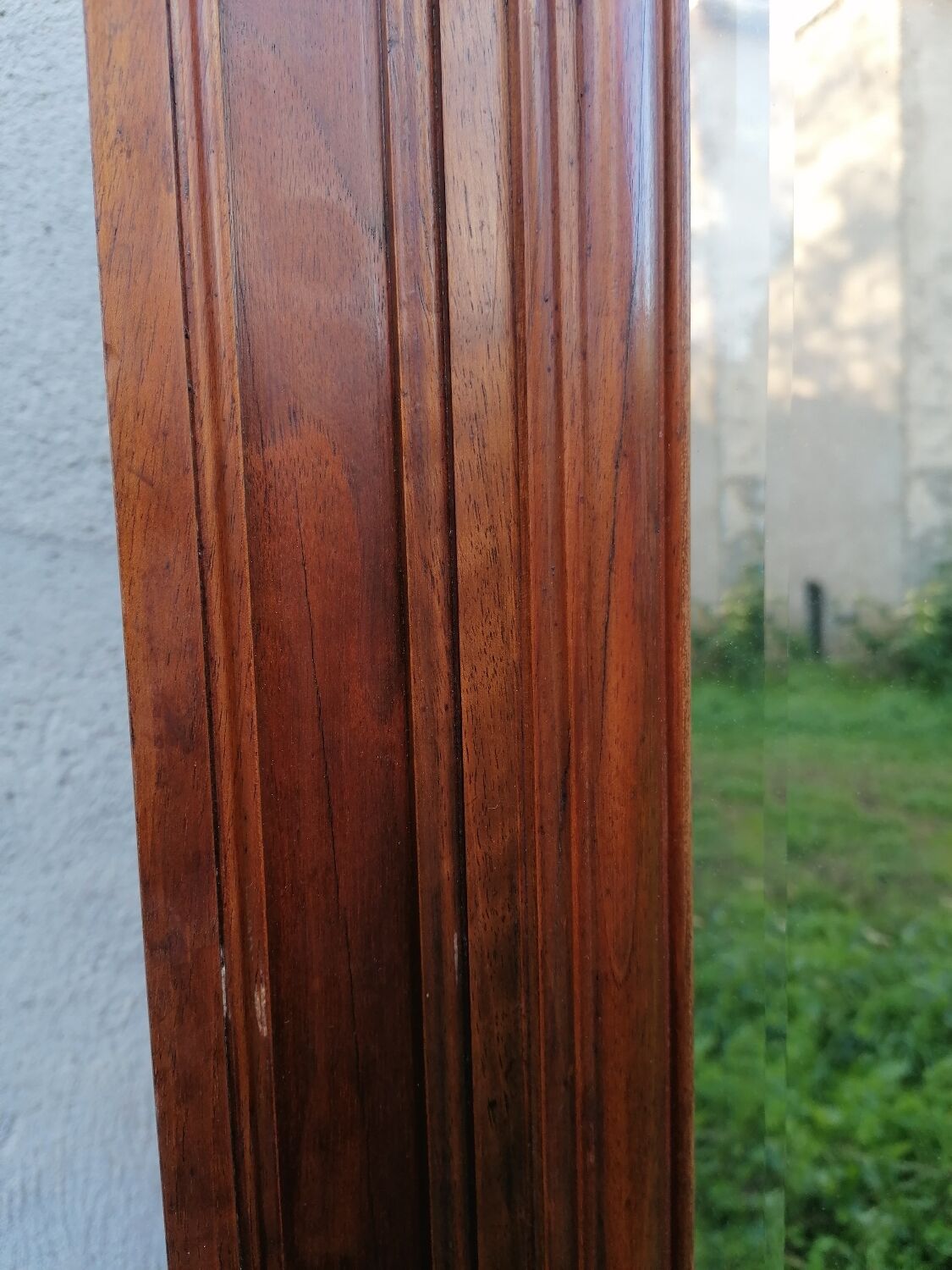 Old beveled solid wood mirror of a cabinet door.