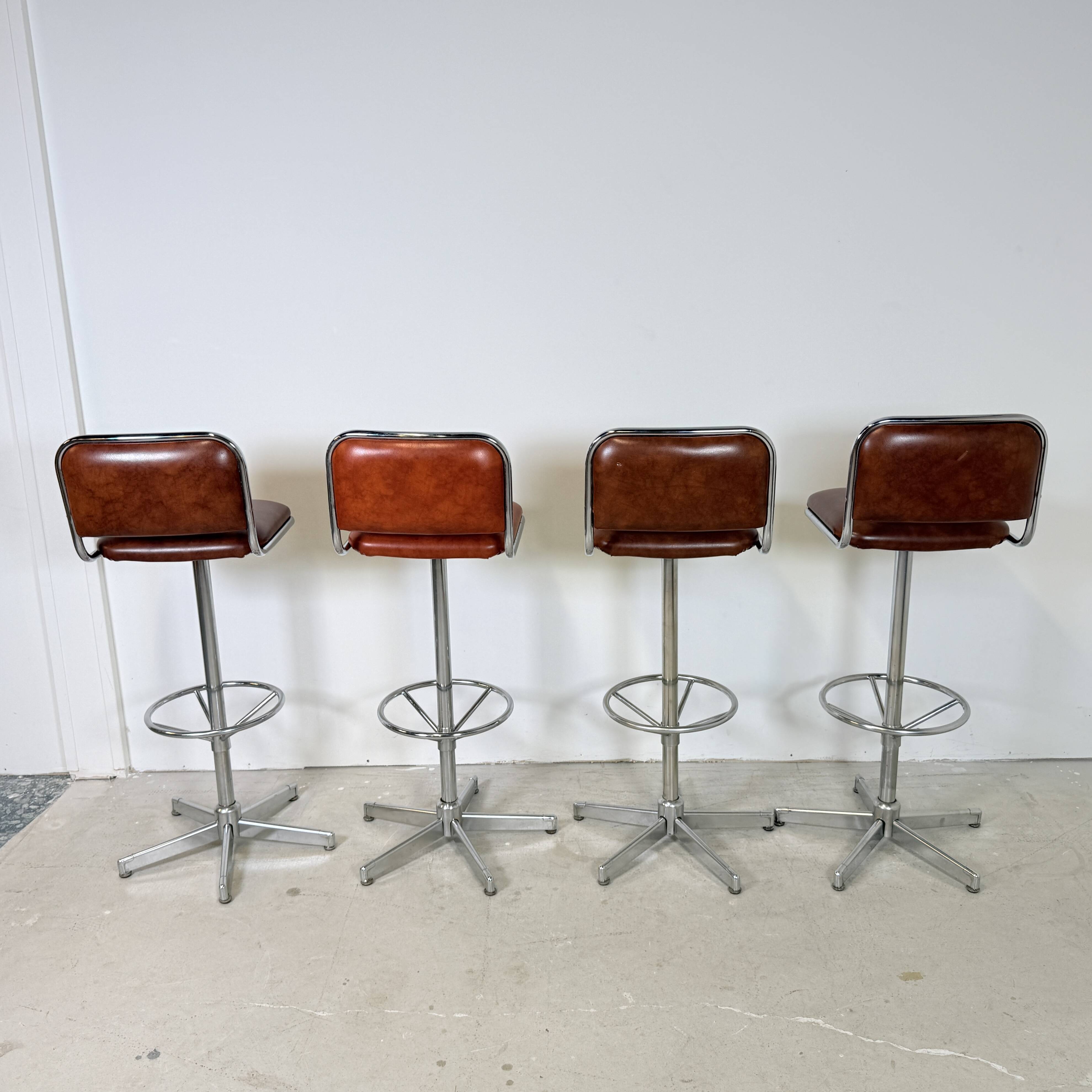 1970s chrome bar stools with cognac-colored faux leather upholstery