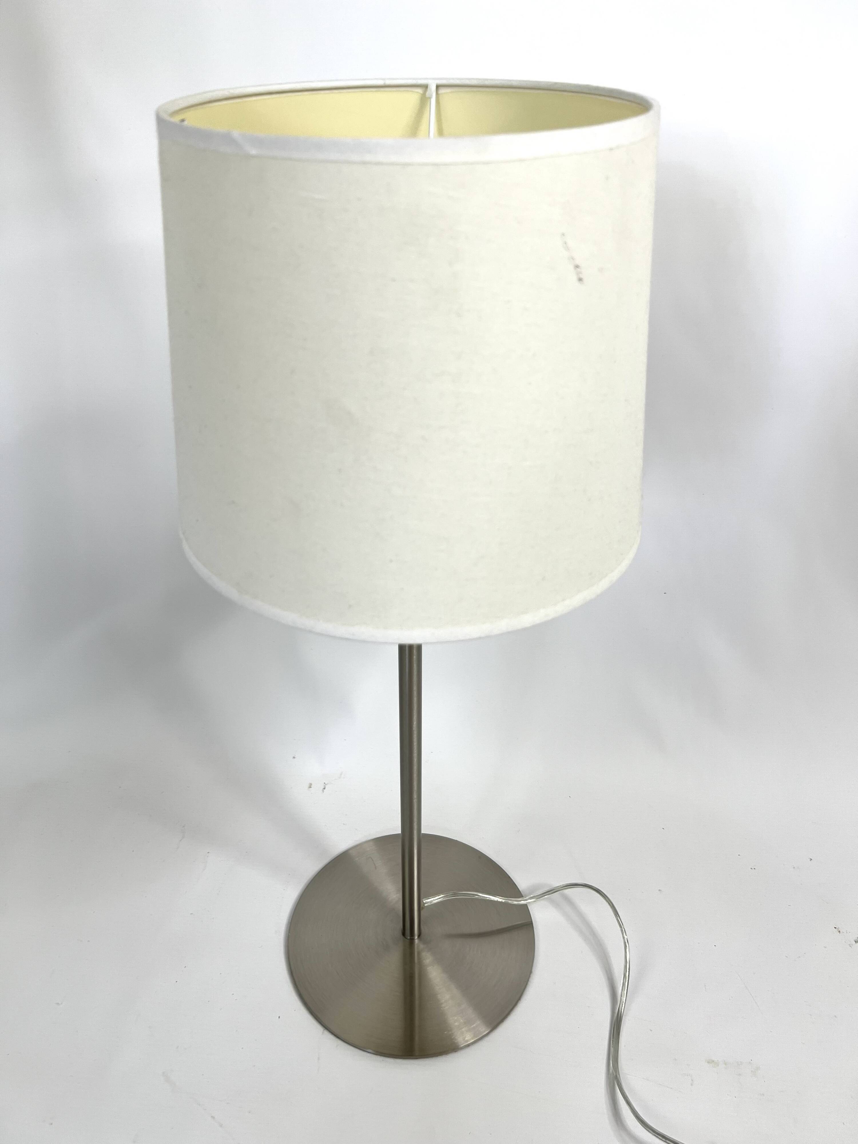 Large brushed metal table lamp with an ecru shade.