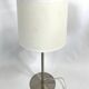 Large brushed metal table lamp with an ecru shade.