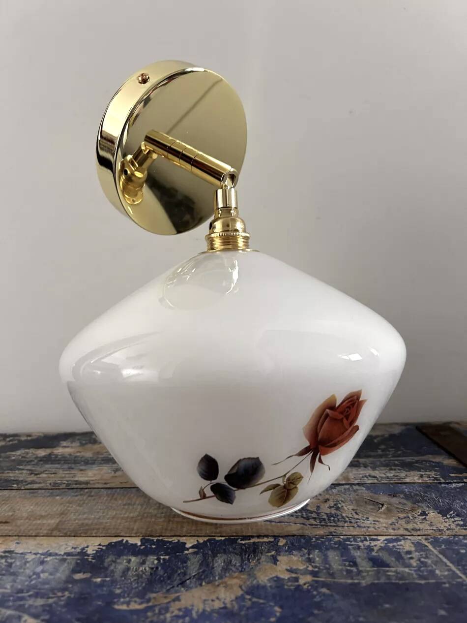 Golden tilting wall light with flowered globe