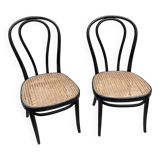 Pair of black curved wooden bistro chairs with caning in Thonet style.