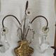 Pair of French antique brass double wall lights with assorted crystals.