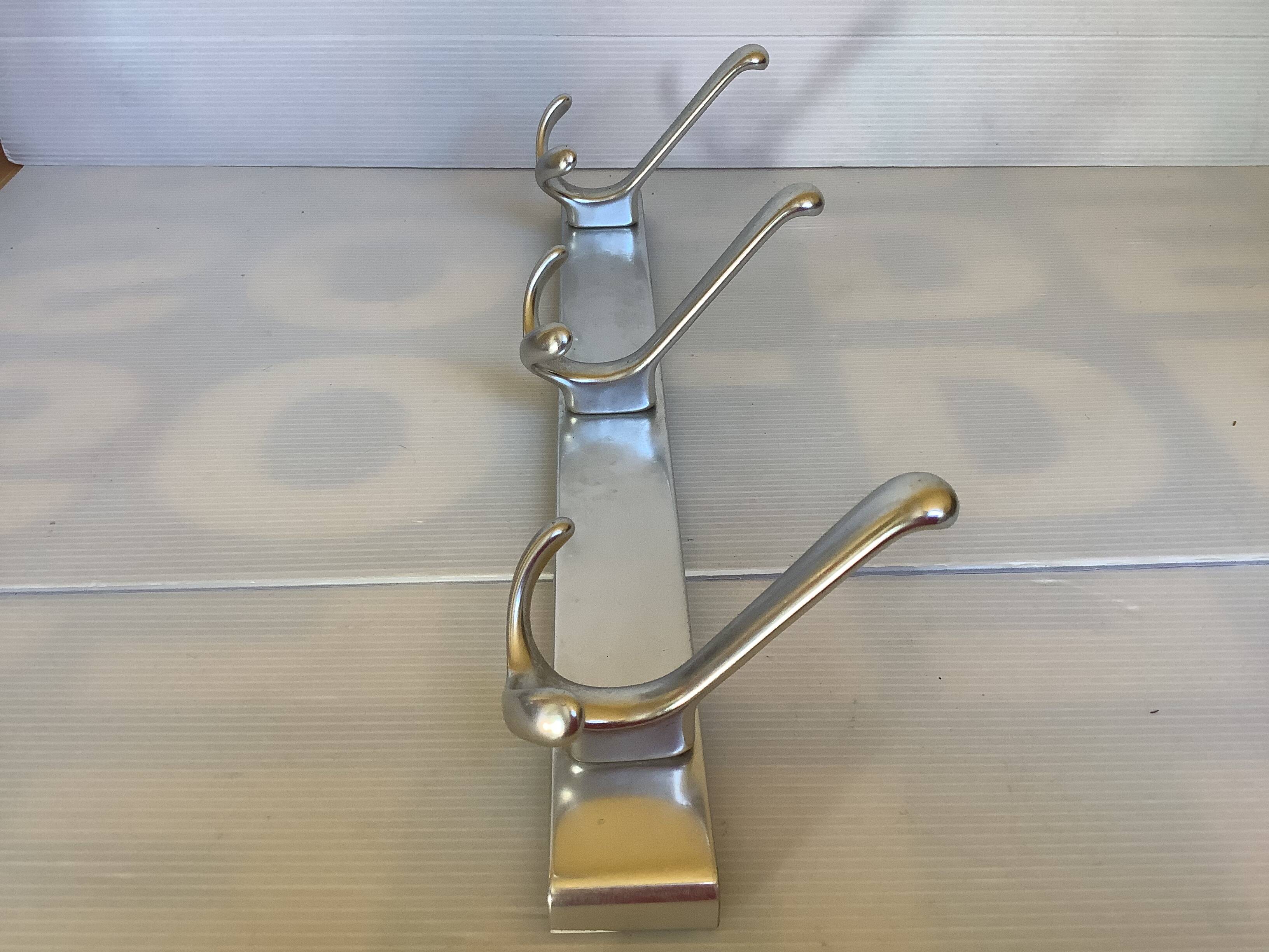 Stainless steel coat rack with three double hooks.