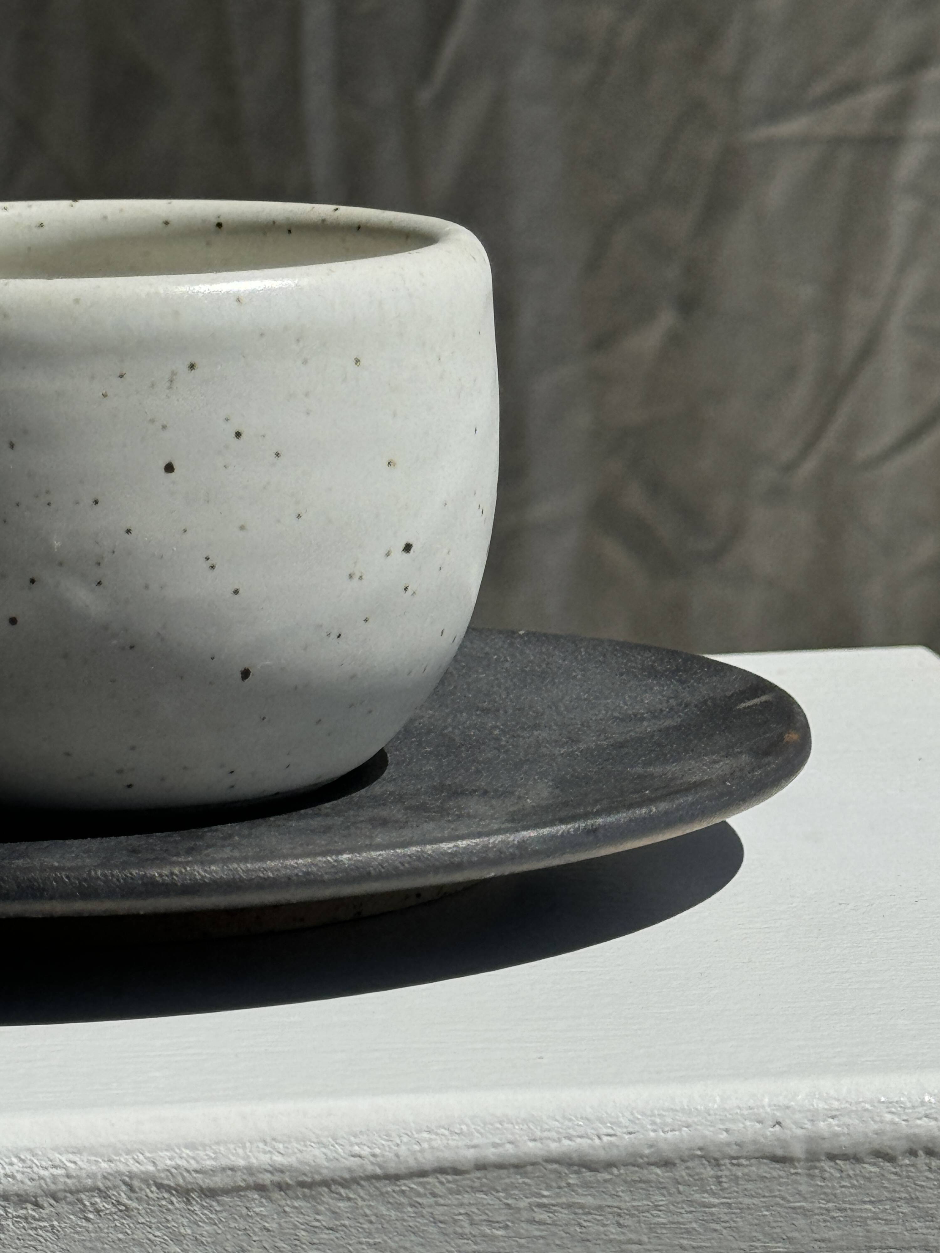 White Indonesian ceramic cup and gray saucer