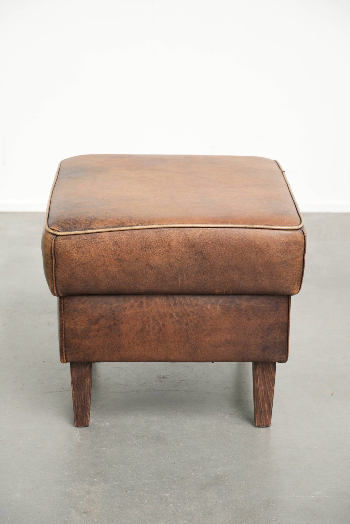 Set of a sheepskin armchair and ottoman finished with matching piping