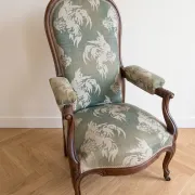 Antique Voltaire armchair in wood and green fabric with floral patterns.