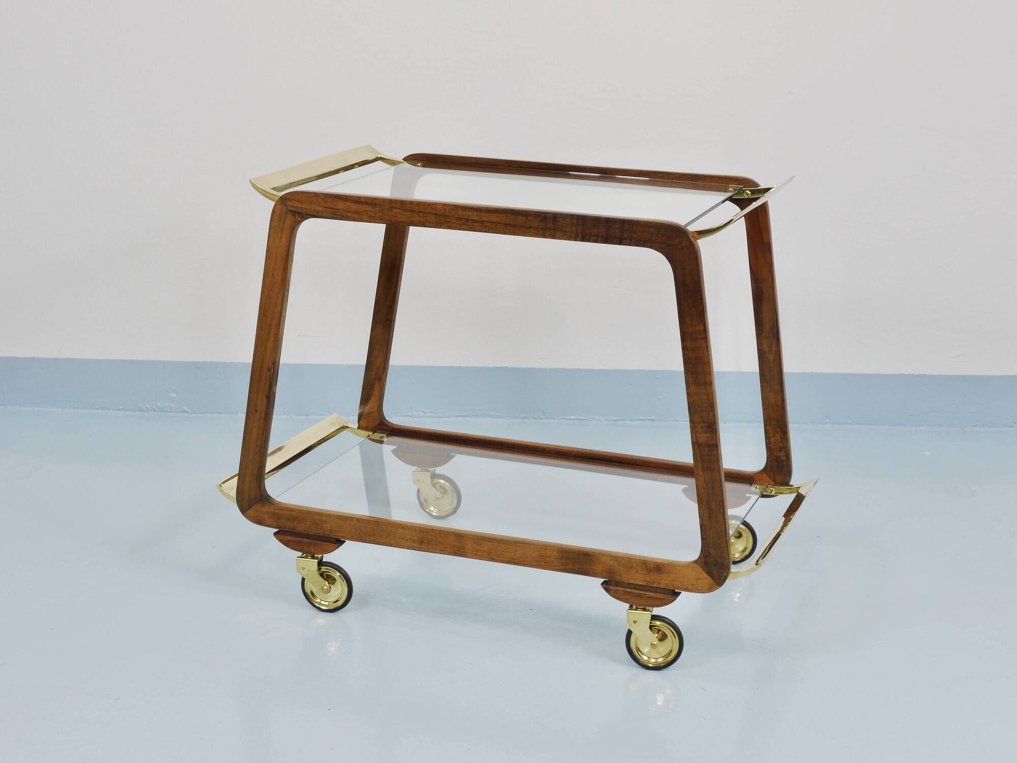 May include: A mid-century modern bar cart with a dark wood frame and two c