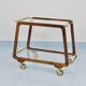 May include: A mid-century modern bar cart with a dark wood frame and two c