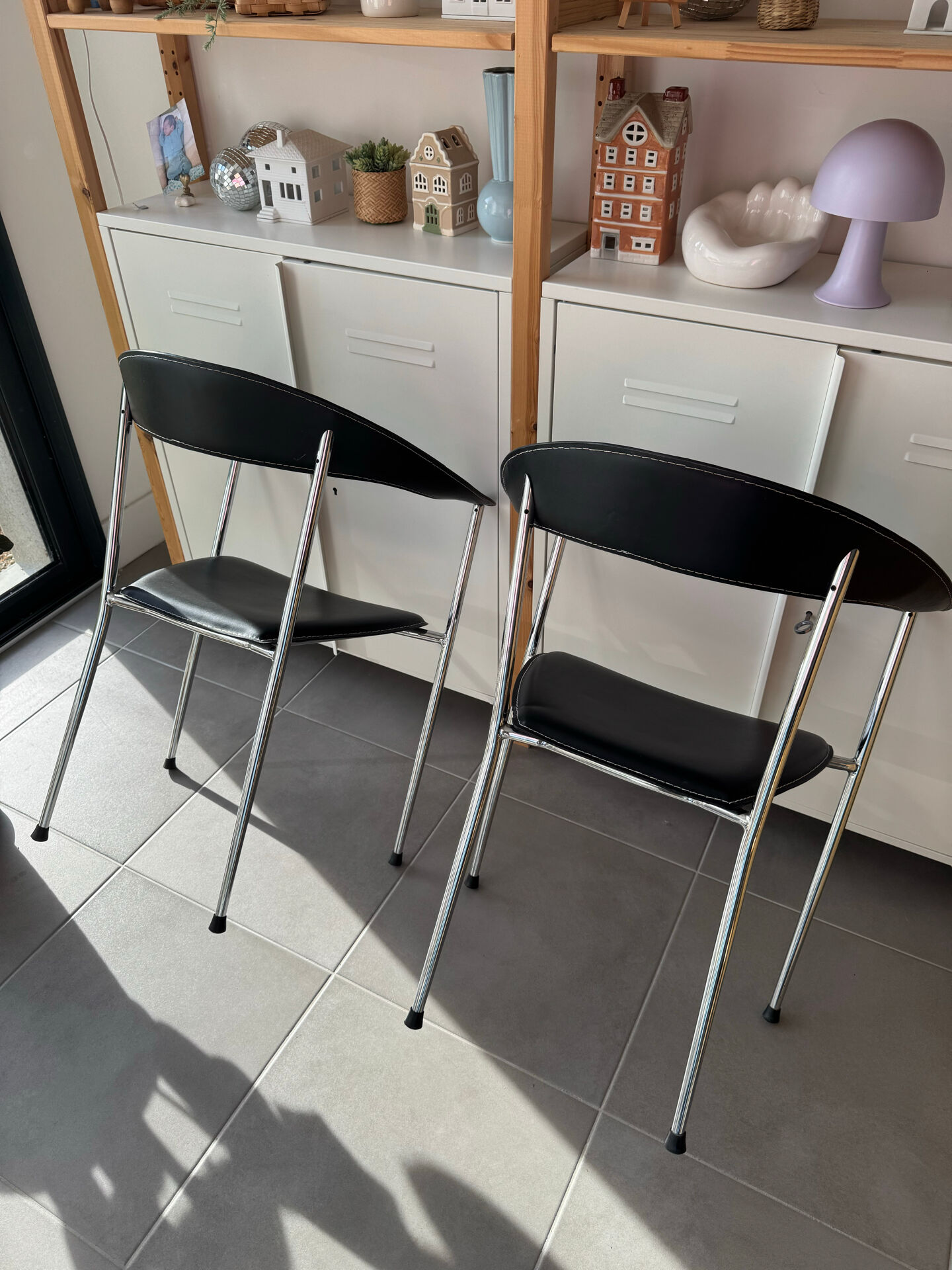 Set of two metal chairs with a brushed finish and black leather.