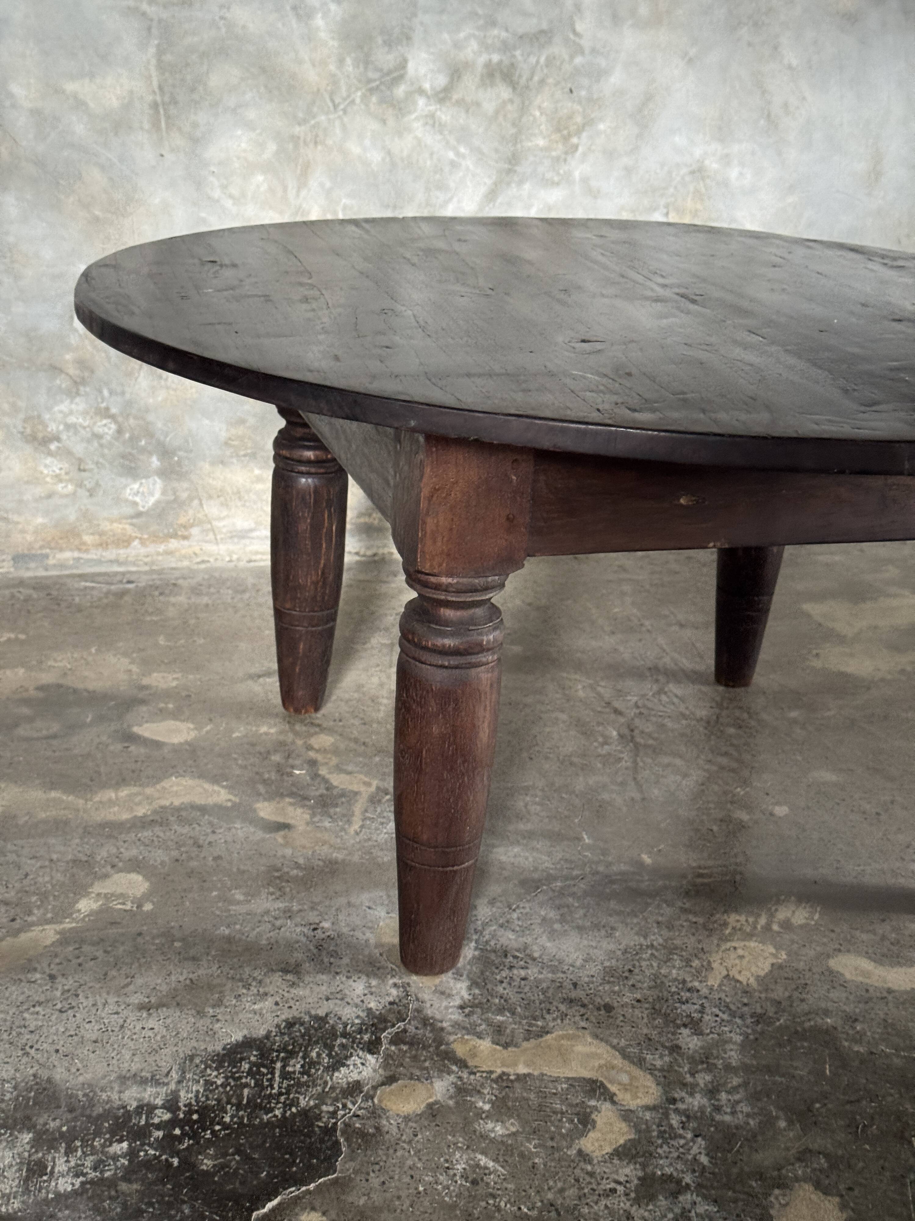 Antique round coffee table in Indonesian teak with turned legs.