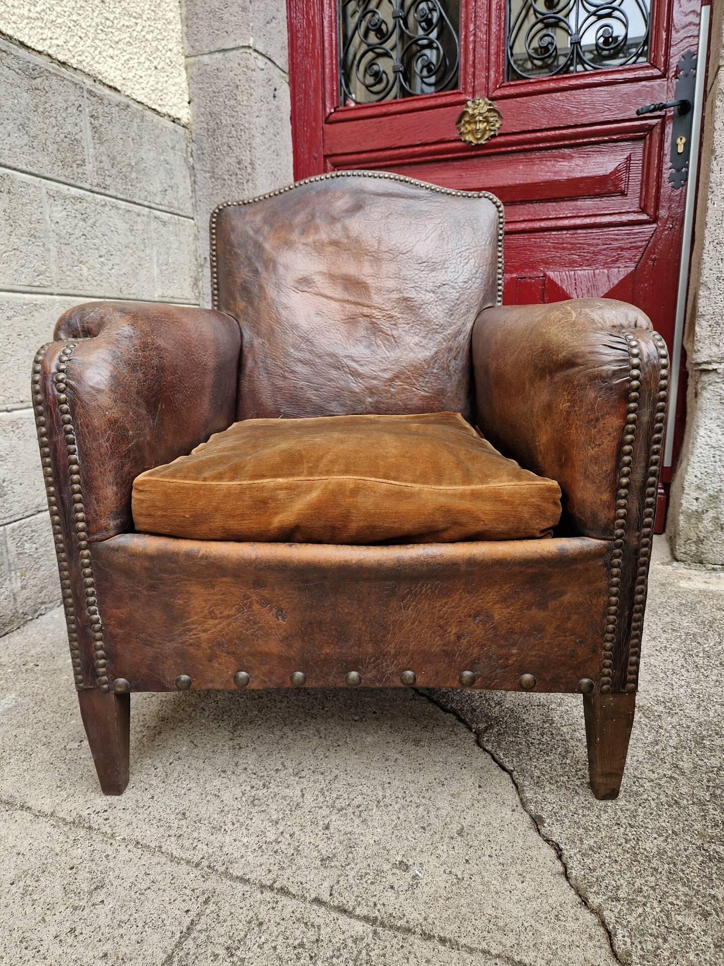 Antique club chair in patinated brown leather, early 20th century English style.