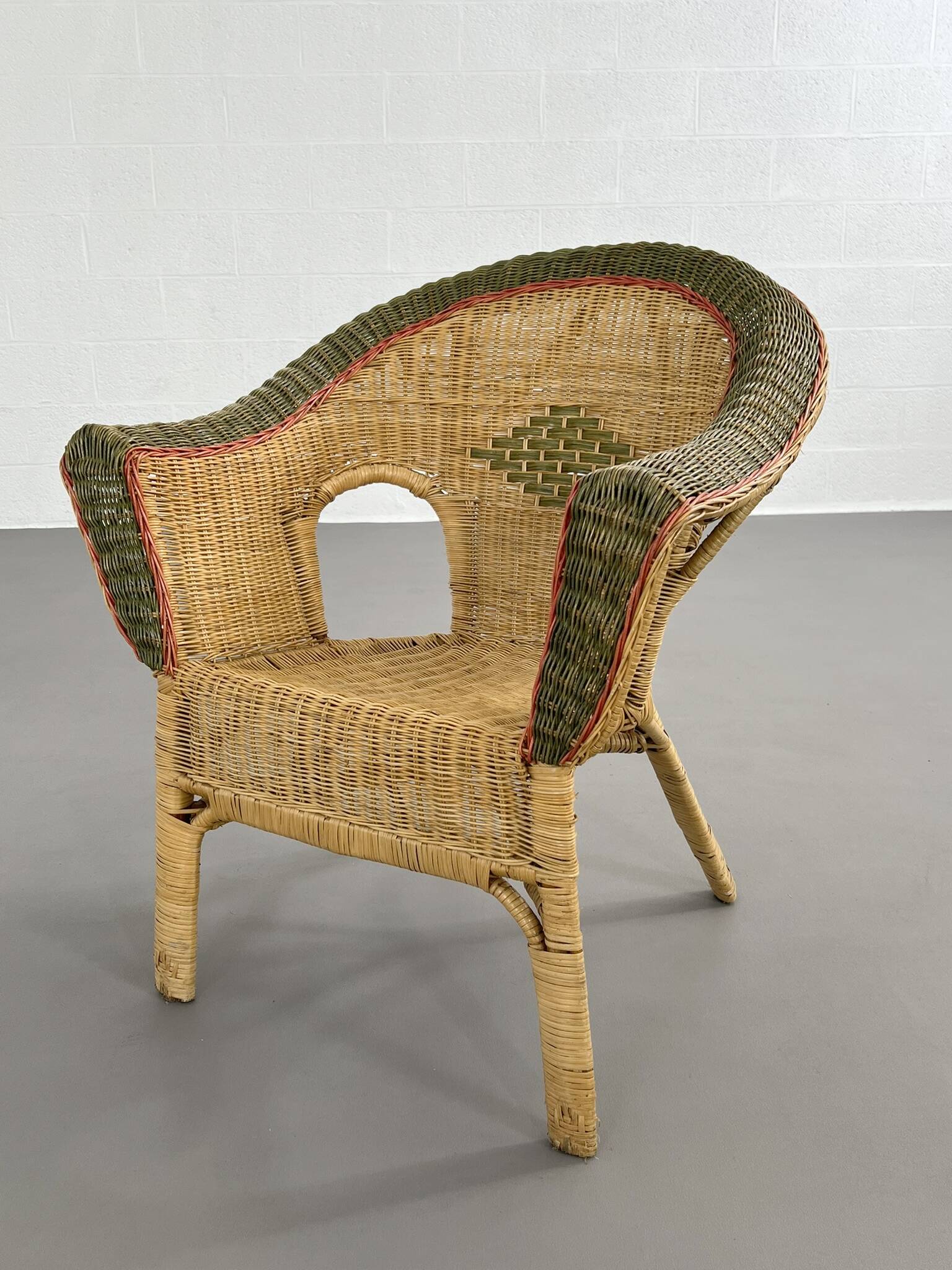 Cabriolet style armchair in rattan, wicker and green and red edging