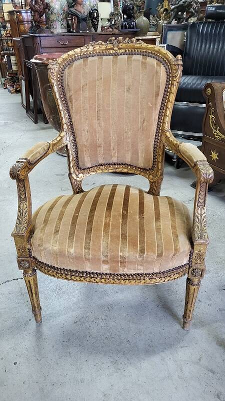 A pair of gilded wooden armchairs in the Louis XVI style.