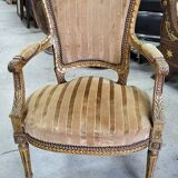 A pair of gilded wooden armchairs in the Louis XVI style.
