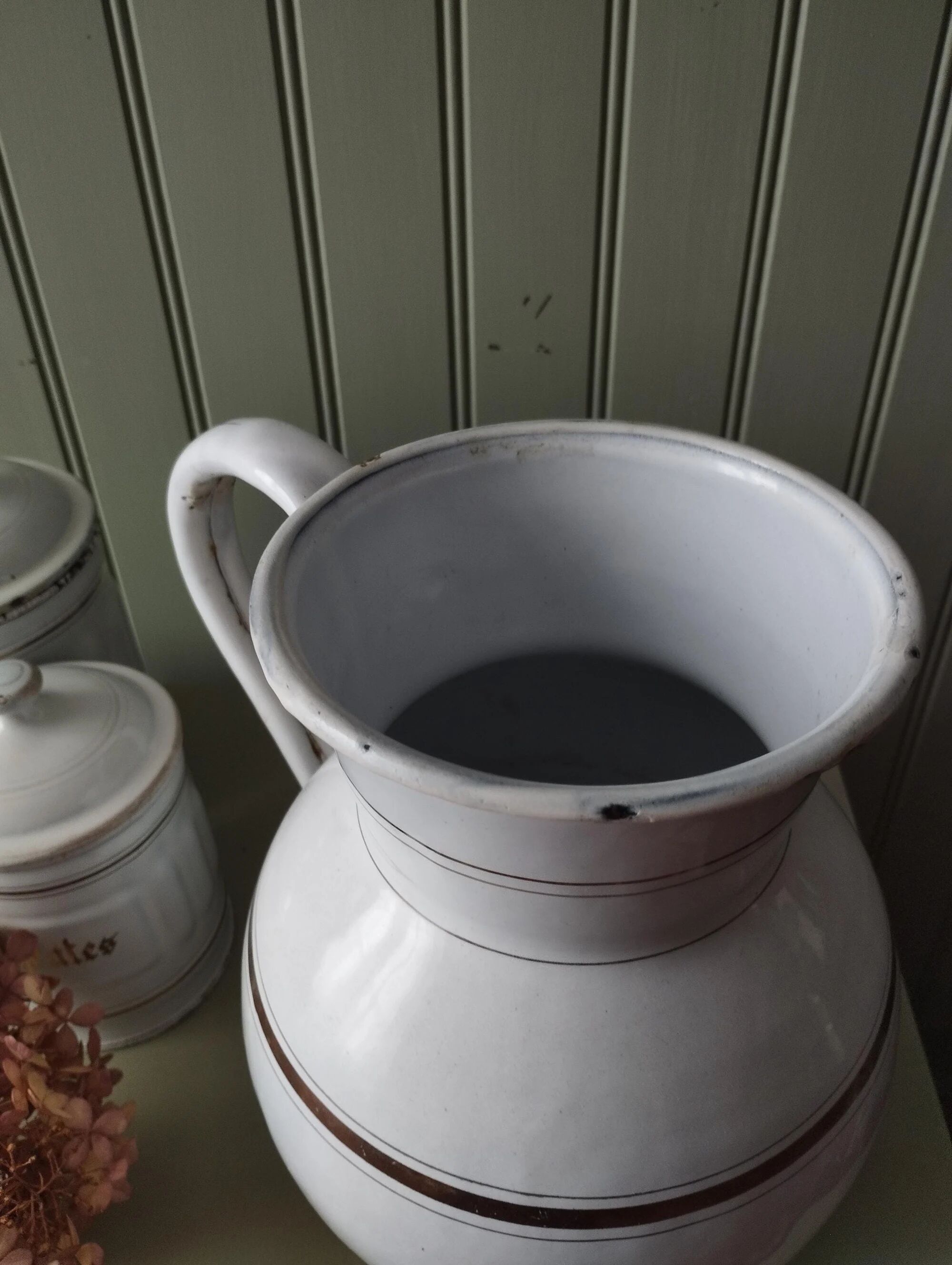 Old enamelled metal jug with gold trim.