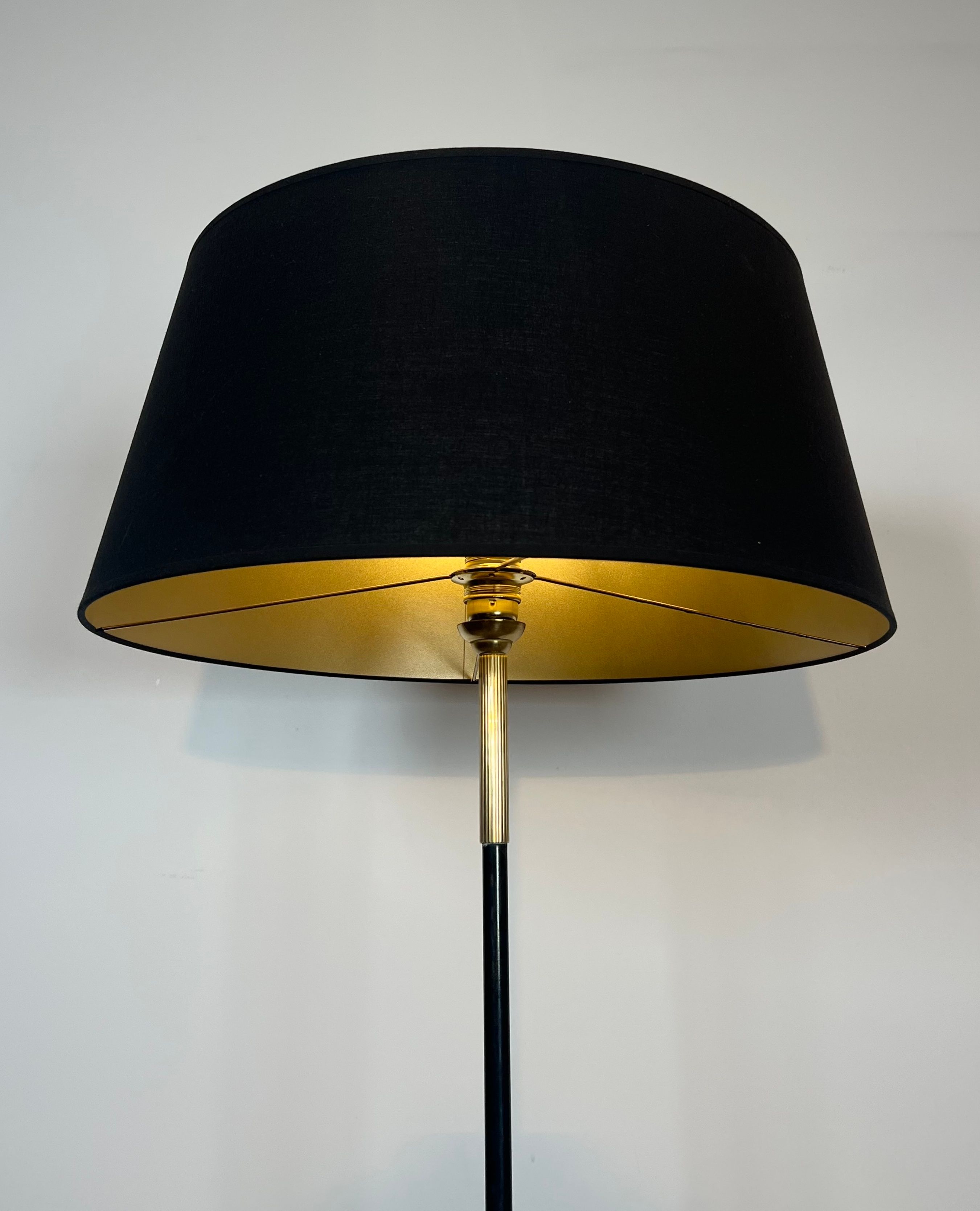 Designer floor lamp in black lacquered metal and brass, incorporating a magazine rack