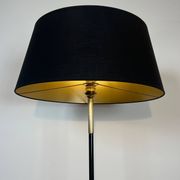 Designer floor lamp in black lacquered metal and brass, incorporating a magazine rack